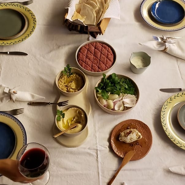 Mesa árabe posta com mezes, quibe e pães da Chef Isadora Marar